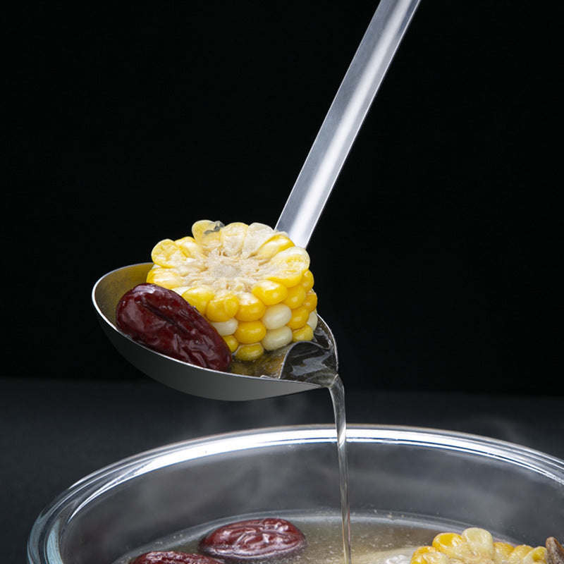 Corn on a spoon being dipped into a pot of soup with a black background