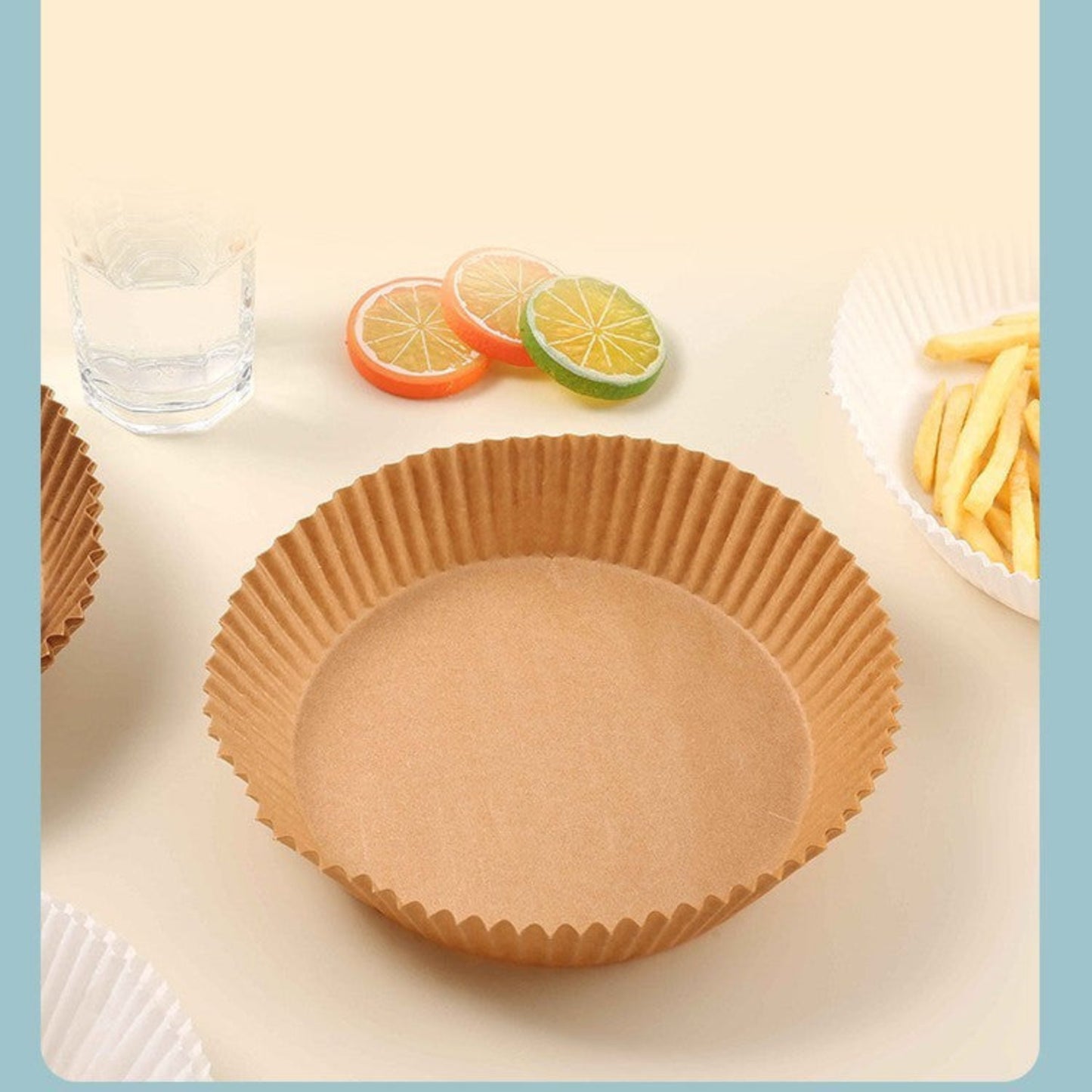 Brown paper cupcake liner on a white surface with fruit slices and a glass of water in the background.