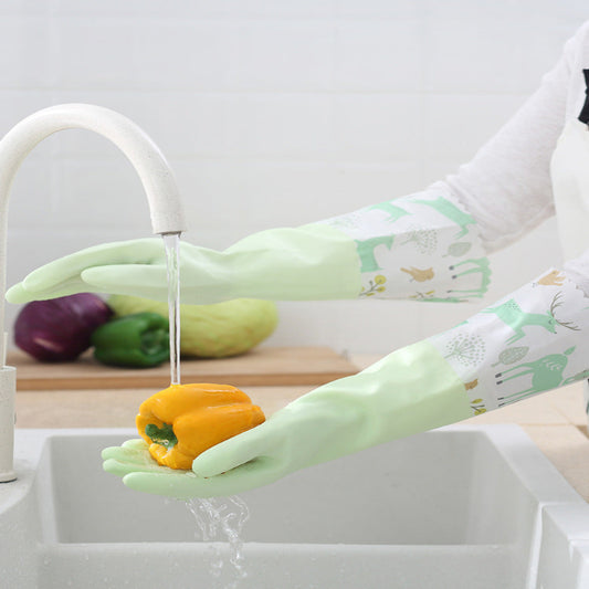 Person washing a yellow bell pepper under running water in a kitchen sink, wearing green gloves with a pattern.