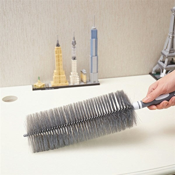 Person using a brush to clean a surface with model buildings in the background