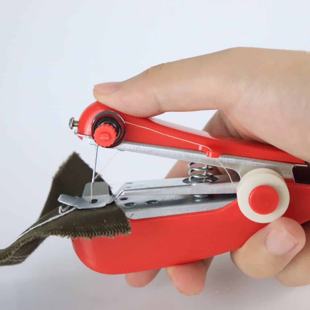 Hand holding a red portable sewing machine on a white background