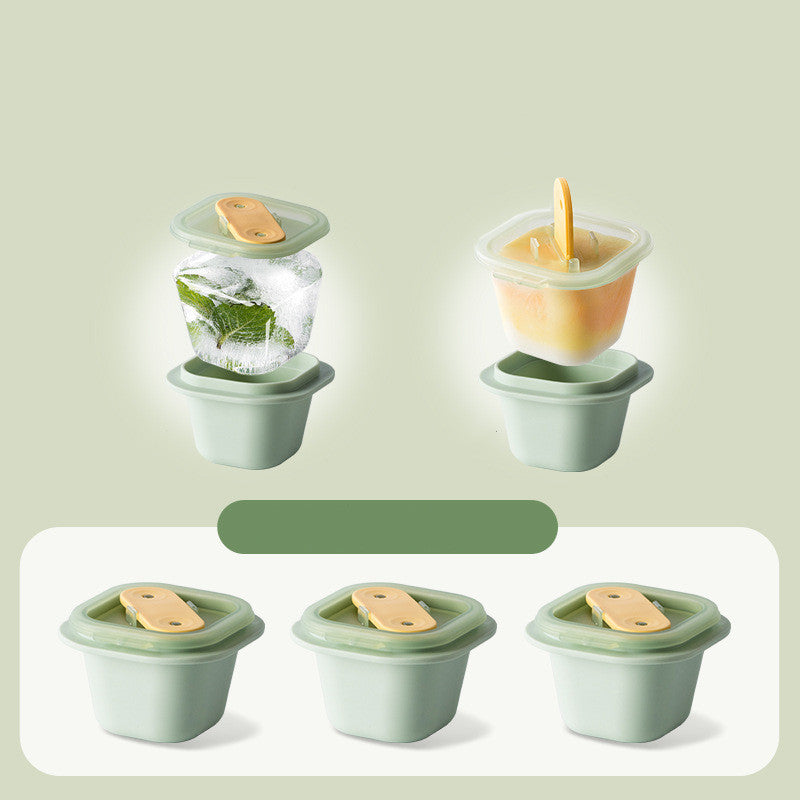 Set of green silicone food storage containers with wooden lids on a light green background.