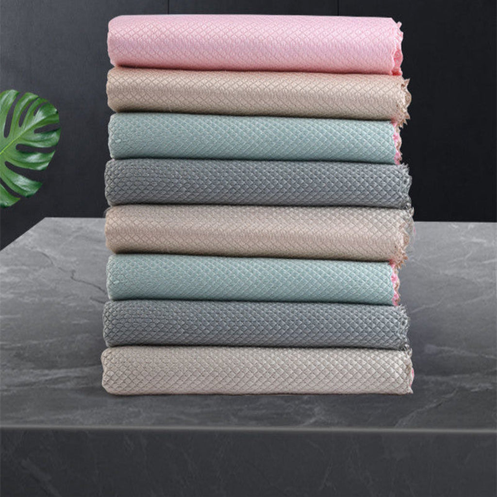Stack of folded towels in various colors on a dark surface with a leaf decoration.