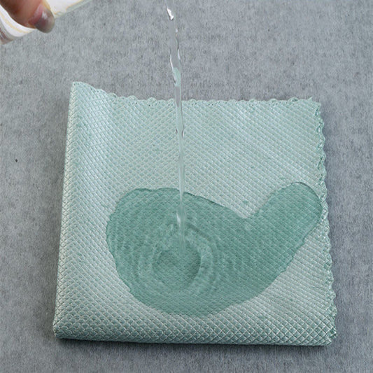 Green fabric with water being poured onto it on a gray background