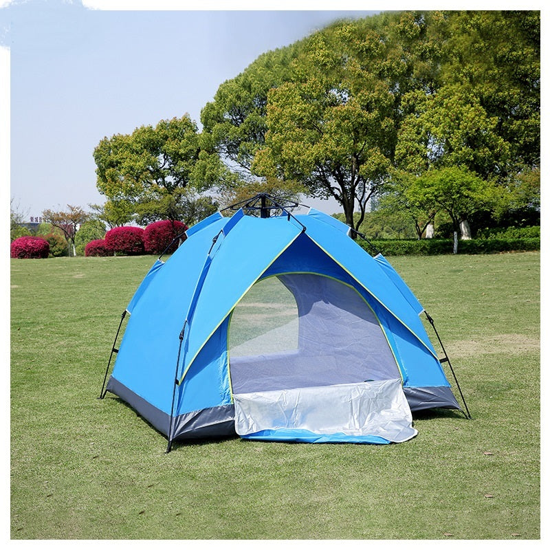 Blue camping tent on grass with trees in the background