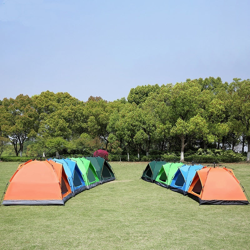 Colorful tents set up on a grassy field with trees in the background