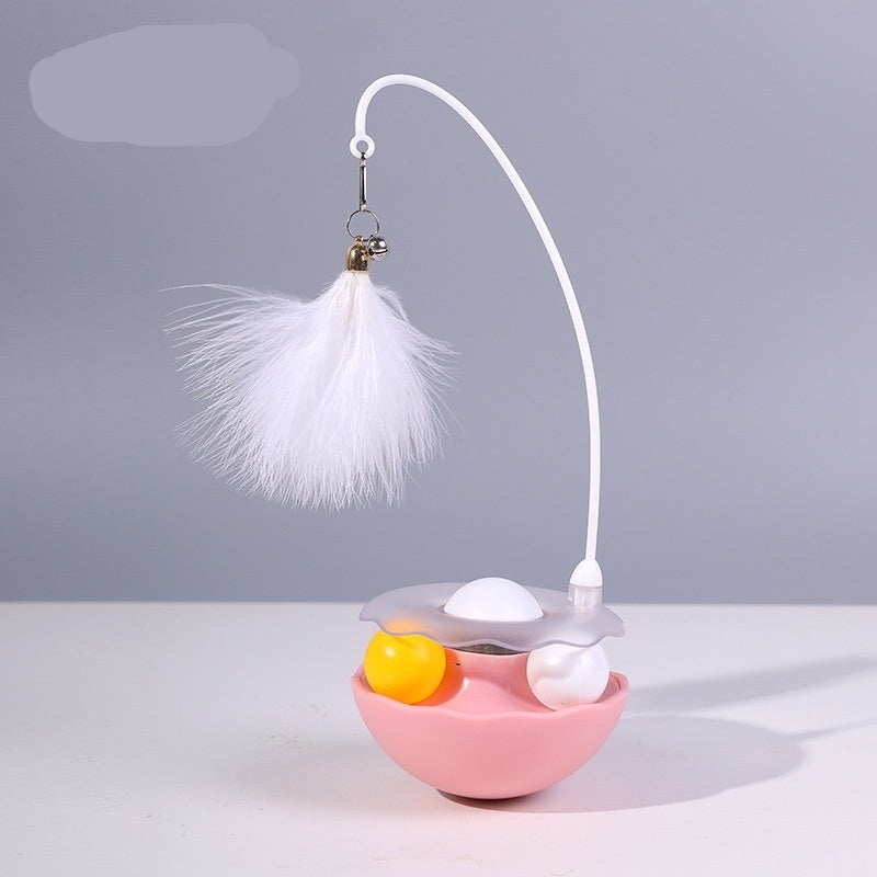 Pink cat toy with a white feather and yellow ball on a gray background