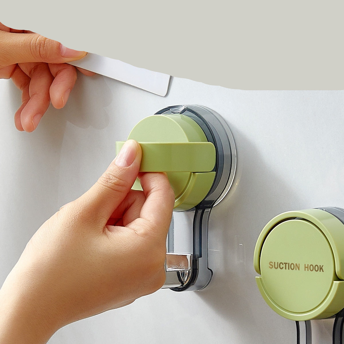 Hand using a green suction hook on a white surface with text about its features.