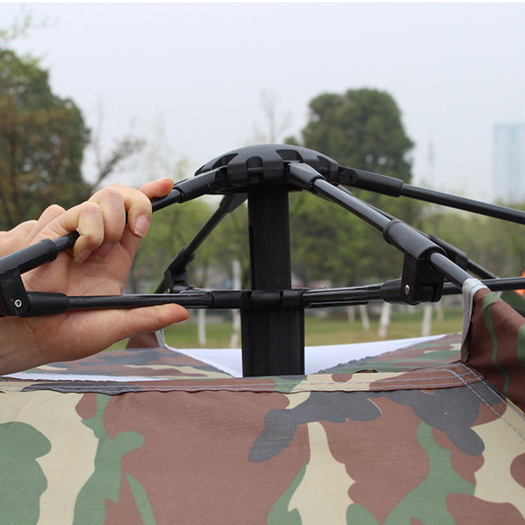 Camouflage canopy with a hand adjusting a support structure outdoors.