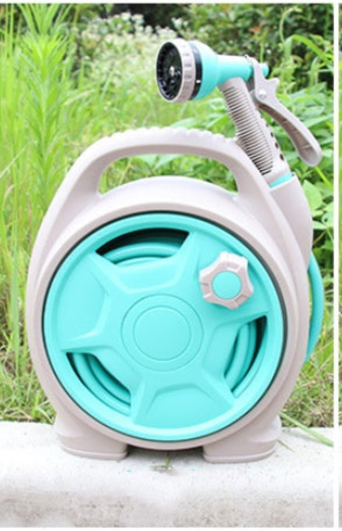 Turquoise and white hose reel with spray nozzle on a natural background