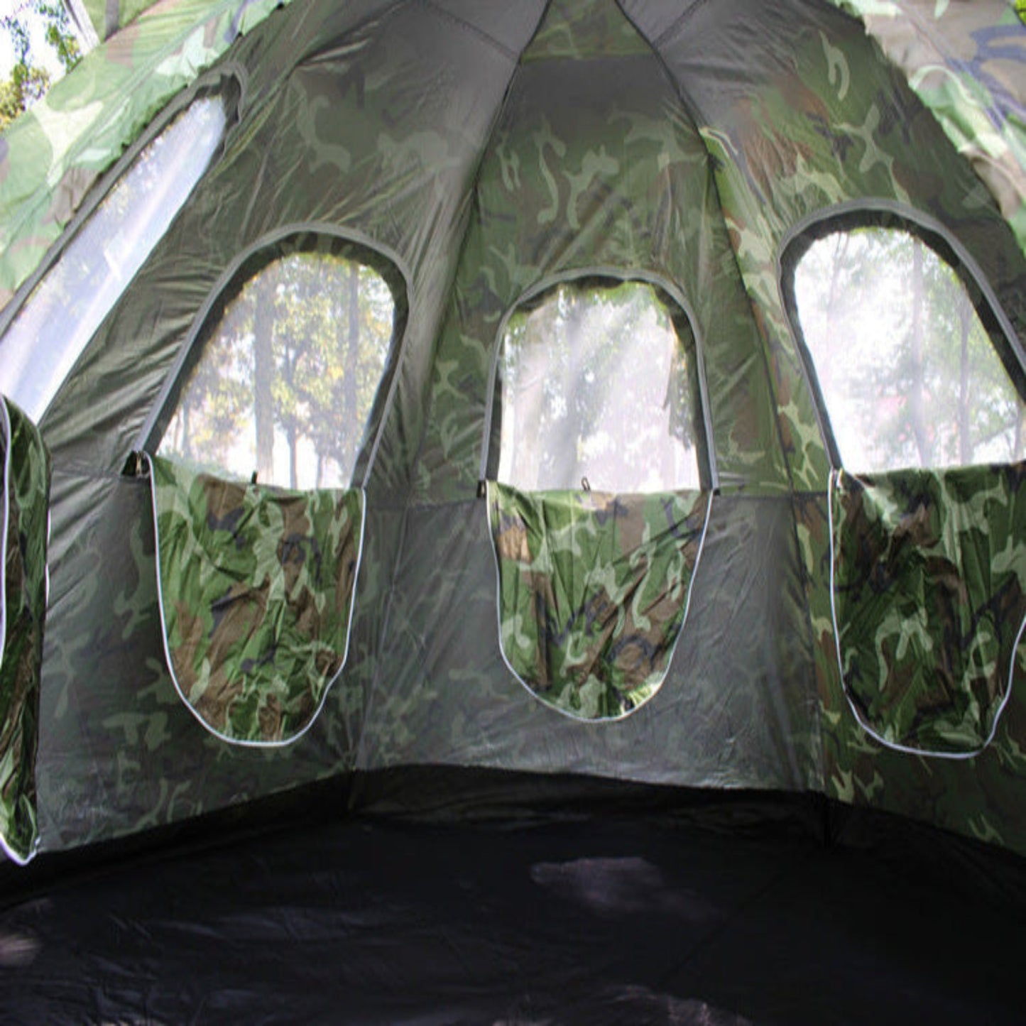 Camouflage-patterned tent interior with windows showing a natural outdoor setting.