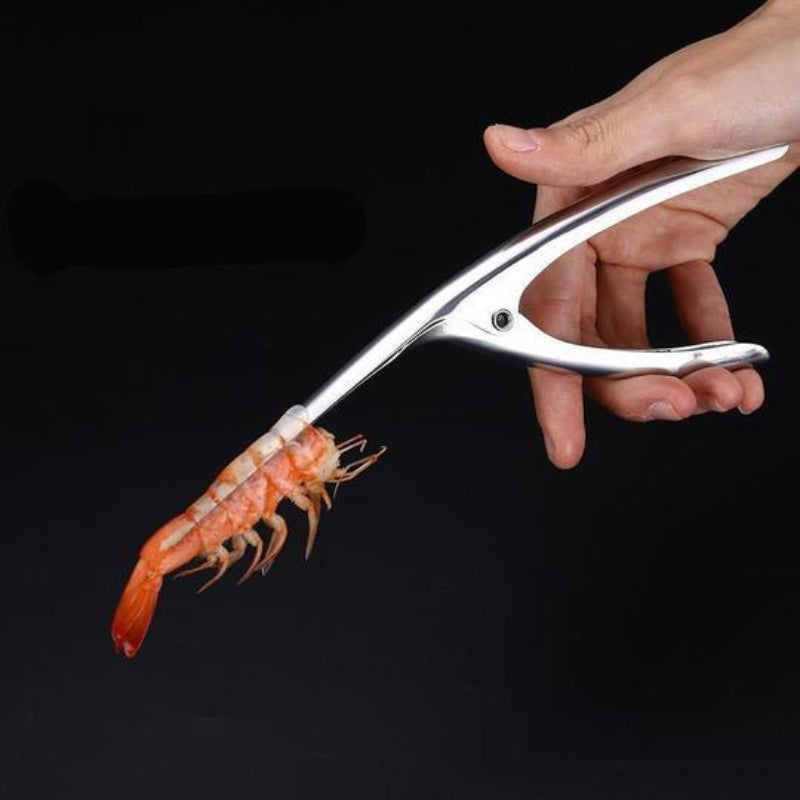 Metallic shrimp peeler being used to remove a shrimp from its shell on a black background