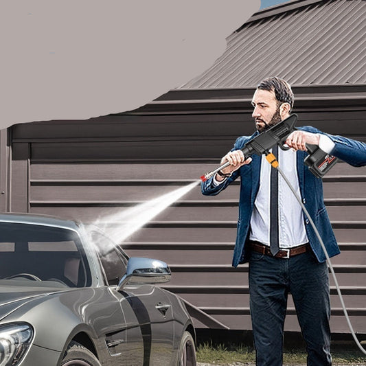 Man using a high-pressure car wash water gun in front of a garage.