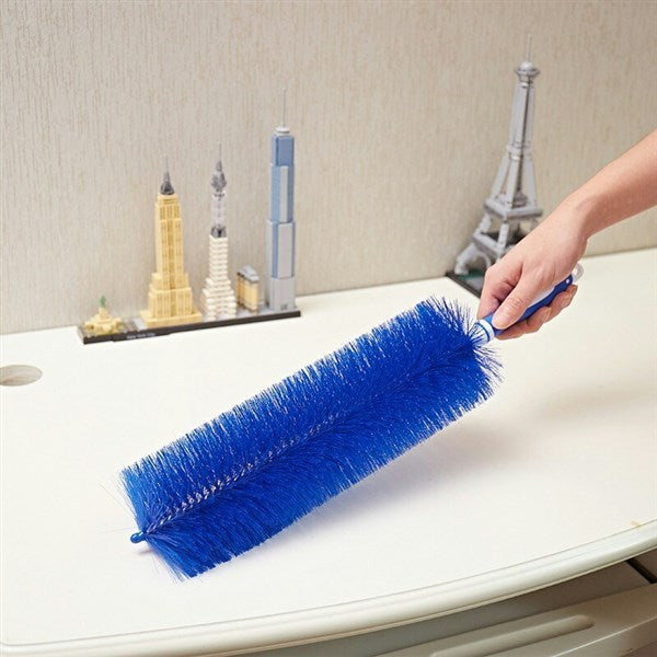 Person cleaning a surface with a blue brush, with decorative items in the background.