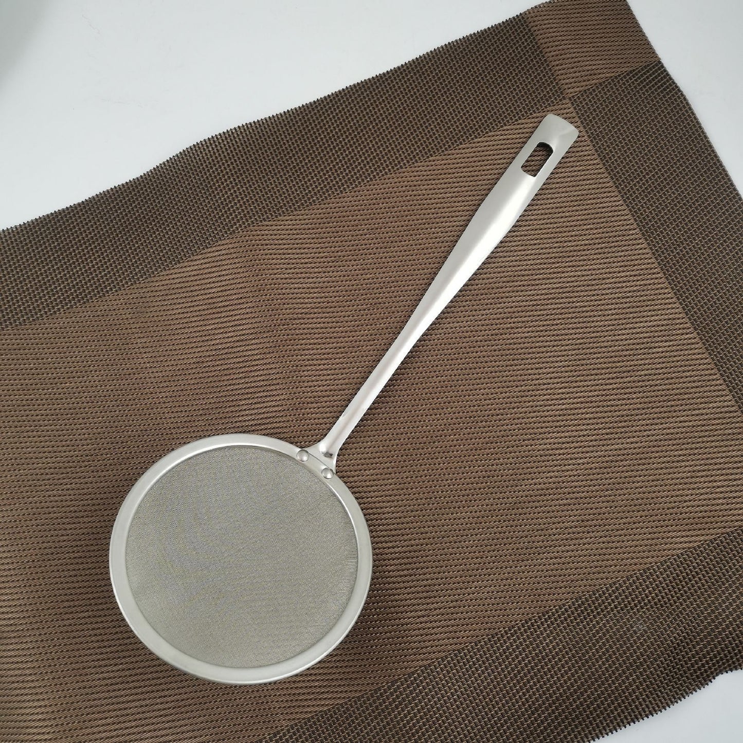 Metallic strainer on a brown textured surface