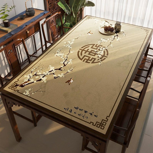 Table with decorative tablecloth featuring floral design and Chinese characters in a room with wooden furniture and plants.