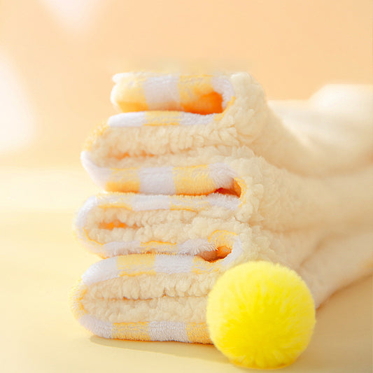 Stack of folded towels with a yellow ball on a light yellow background
