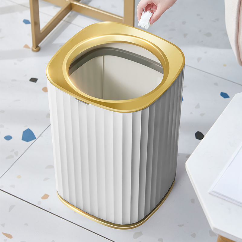 White trash bin with gold rim on a light-colored floor