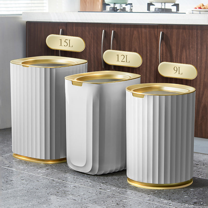 Three cylindrical trash bins with gold accents on a kitchen floor.