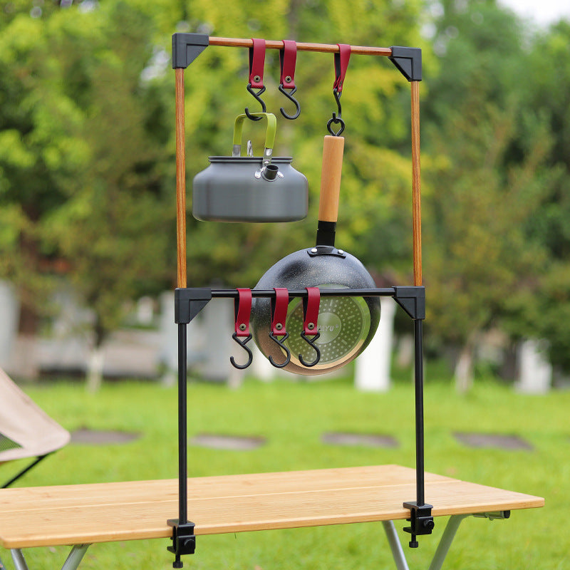 Camping cookware stand with pots and pans on a grassy outdoor background
