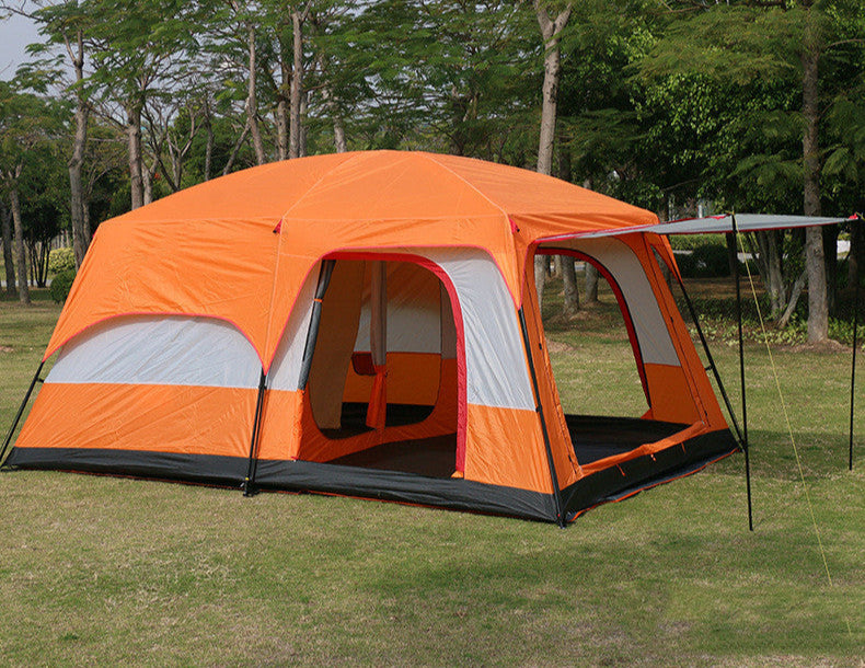 Orange camping tent with attached side awning on grassy area with trees in the background