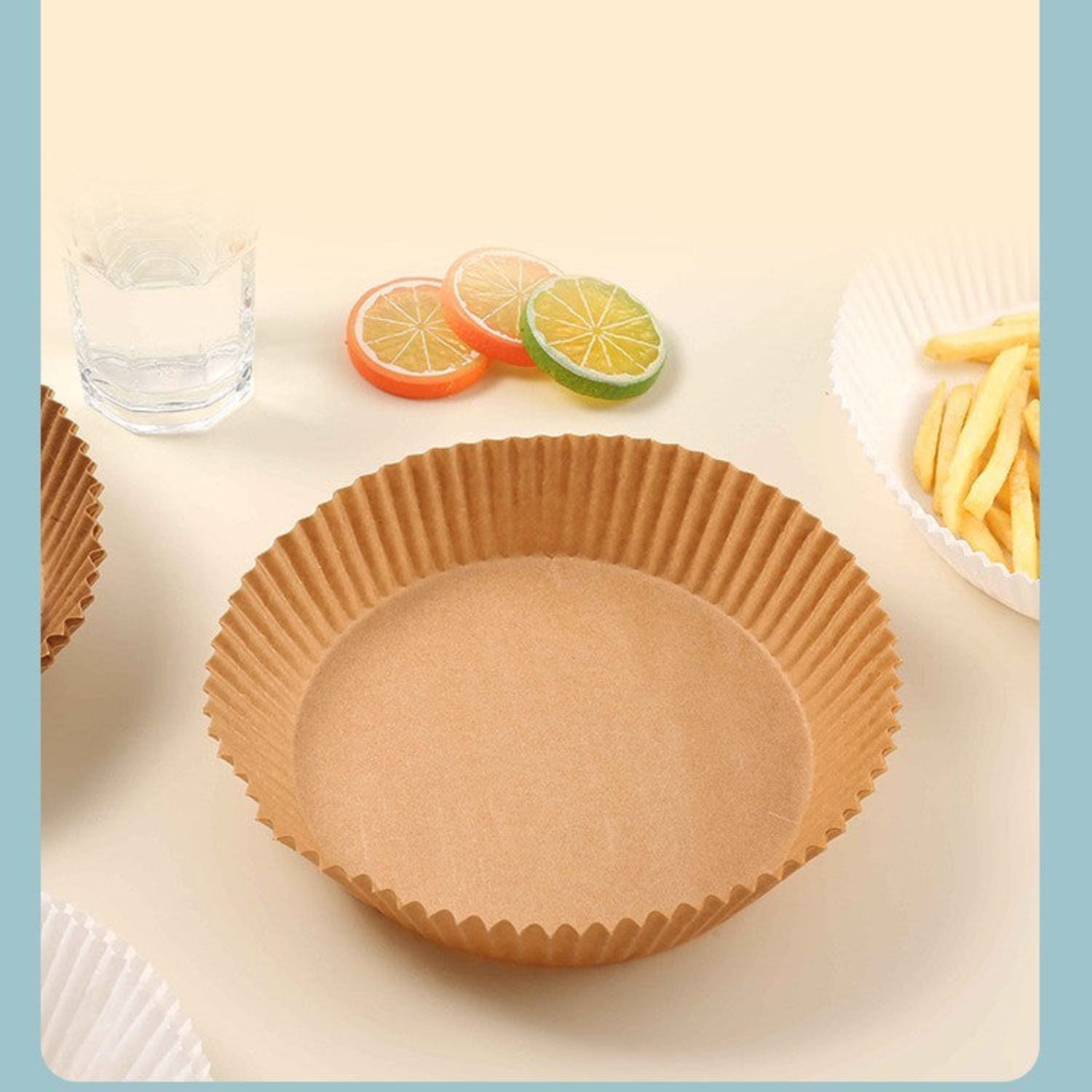 Brown paper cupcake liner on a white surface with fruit slices and a glass of water in the background.
