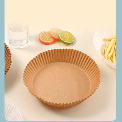 Brown paper cupcake liner on a white surface with fruit slices and a glass of water in the background.