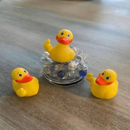 Three yellow rubber duck toys on a wooden surface with a clear crystal ball in the center.