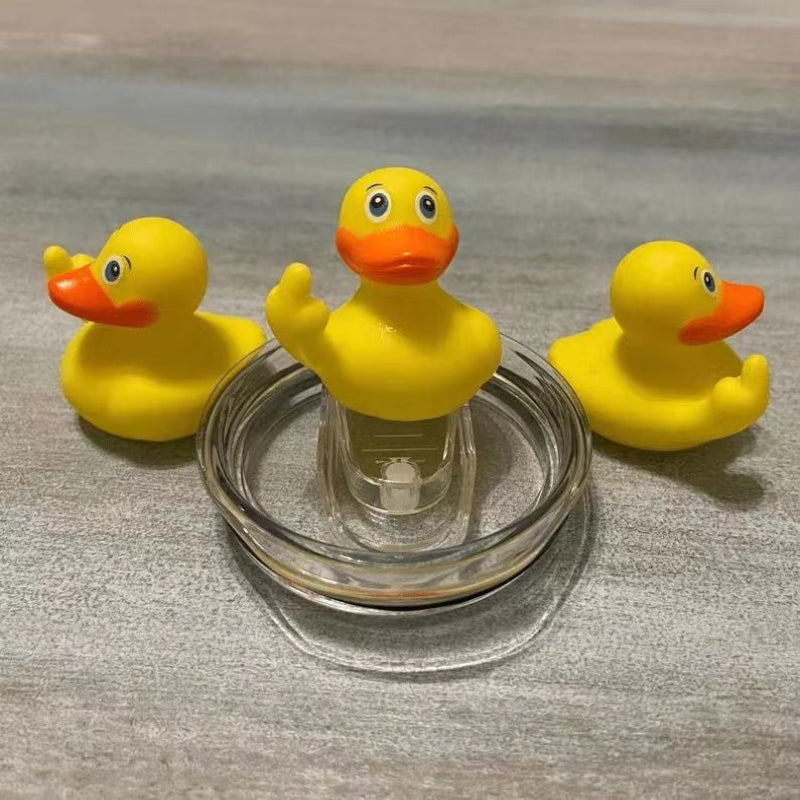 Three yellow rubber ducks with orange beaks and feet on a metallic surface.