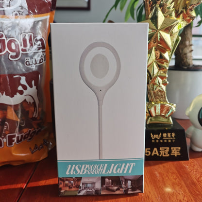 Box of a USB desk light on a table with snacks and a trophy in the background