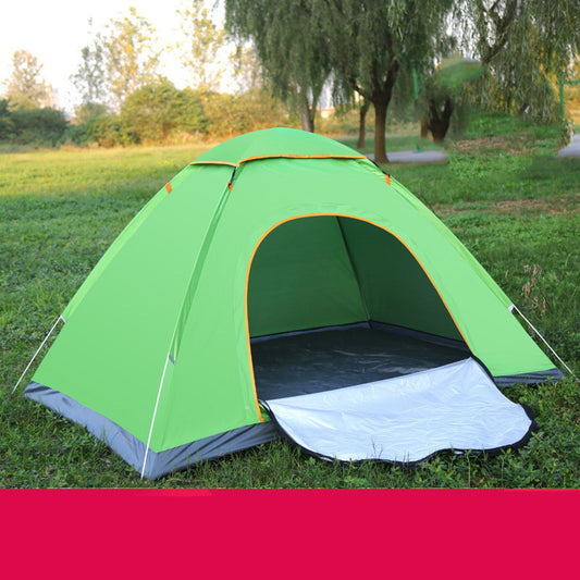Green camping tent set up in a grassy field with trees in the background