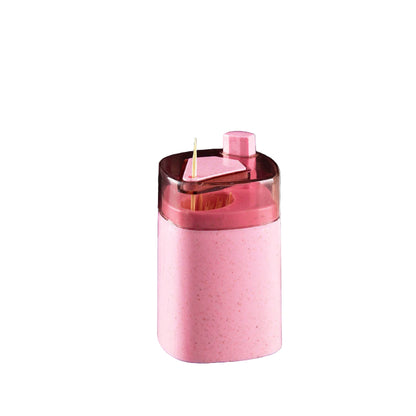 Pink toothpick holder with measurements on a gray surface with coffee beans and a white container.