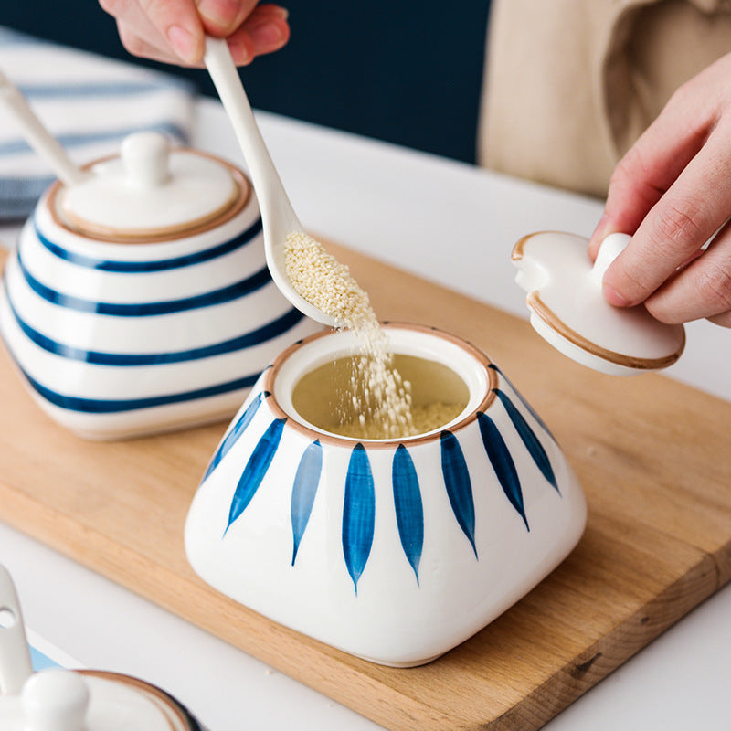 Ceramic container with blue leaf patterns on a wooden board, being filled with a white powder.
