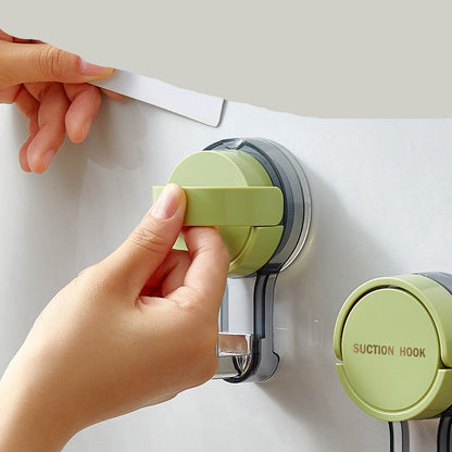 Hand using a green suction hook on a white surface with text about its features.
