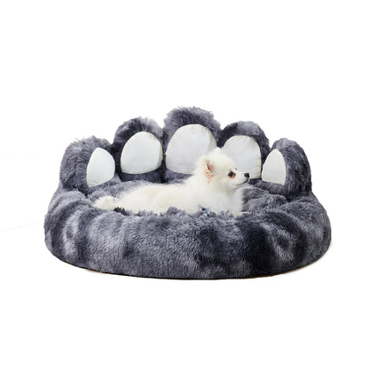 Gray paw-shaped pet bed with a small white dog inside on a white background
