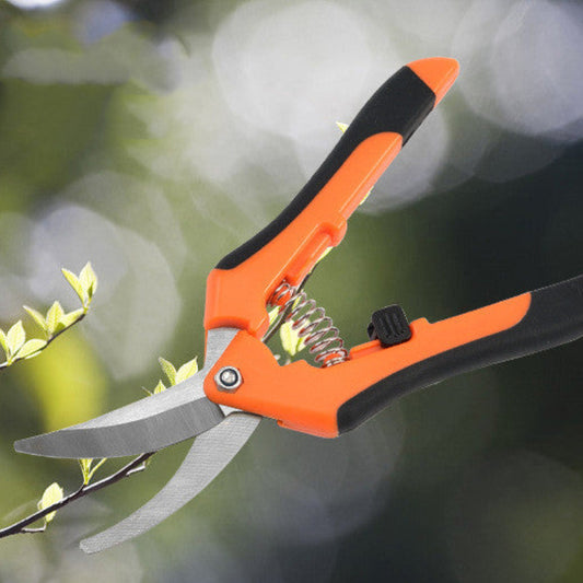 Orange and black gardening shears with a blurred green background