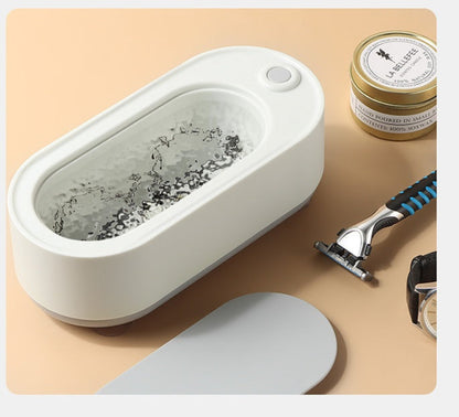 White electric razor cleaner with a razor and shaving cream on a beige surface