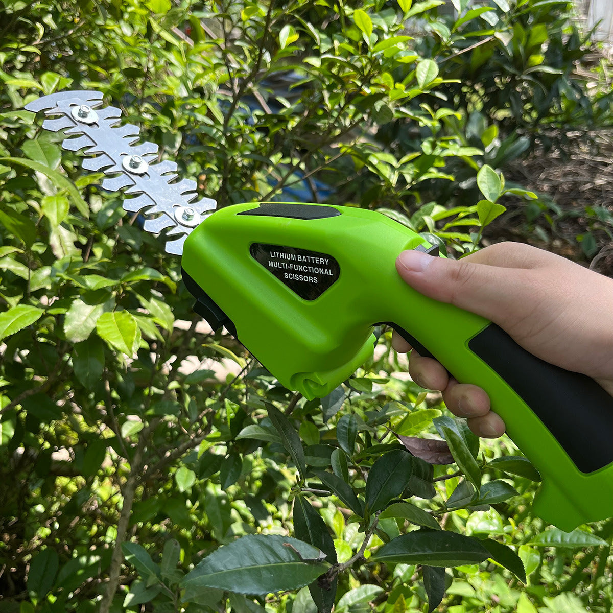 Green battery-powered pruner being used on a bush