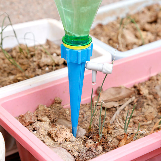 Garden watering system with a blue and green plastic device in a pink container with plants.