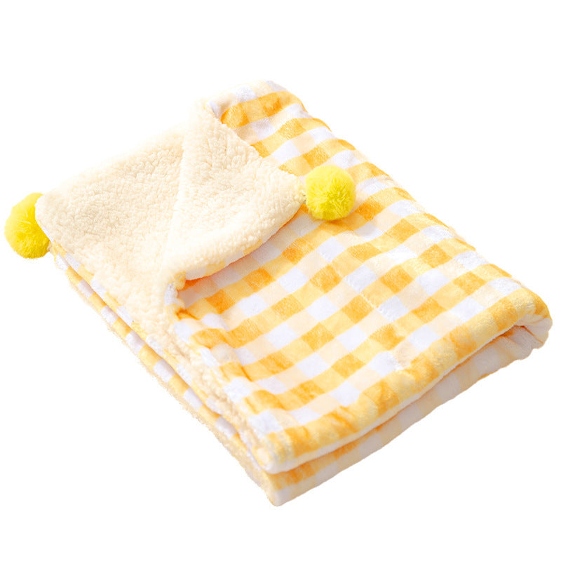 Yellow and white checkered blanket with pom-pom accents on a white background