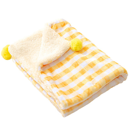 Yellow and white checkered blanket with pom-pom accents on a white background