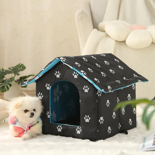 Black pet house with white paw prints on a soft surface, with a small dog sitting inside.