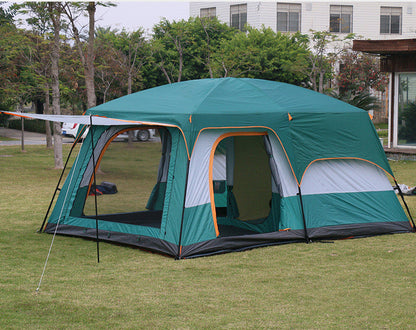 Green camping tent with attached side room on grass, building in background