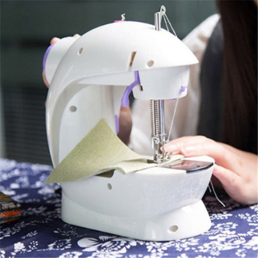 Person using a small white sewing machine on a blue floral tablecloth.