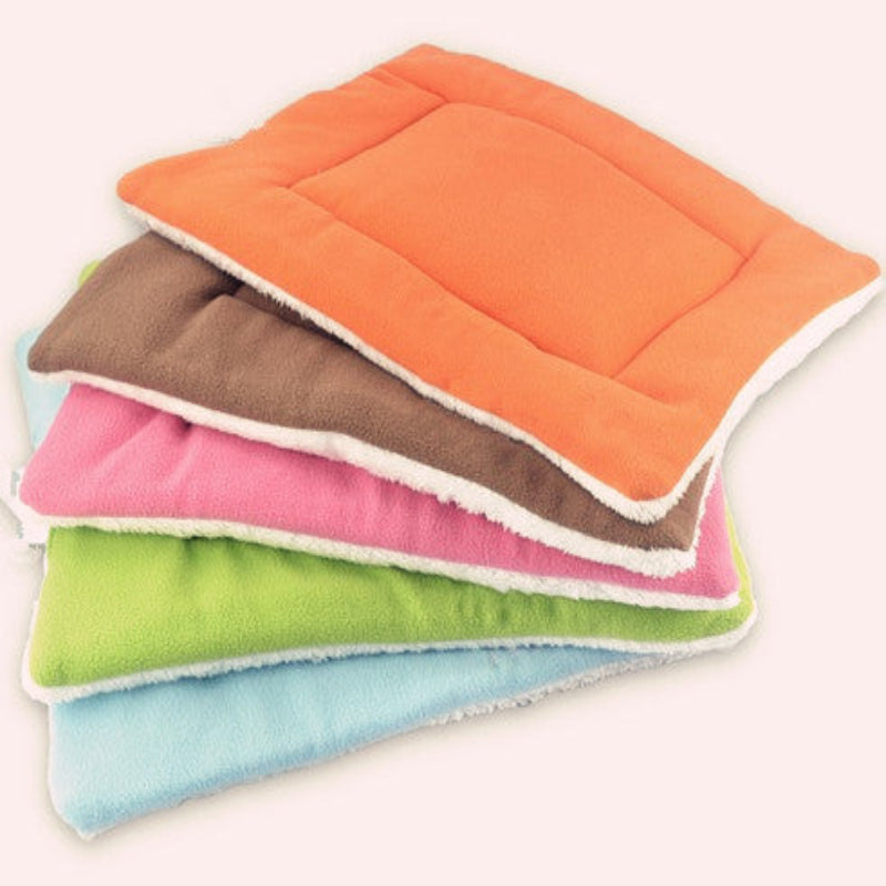 Stack of colorful quilted mats in orange, brown, pink, green, and blue on a white background.