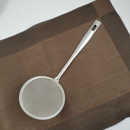 Metallic strainer on a brown textured surface