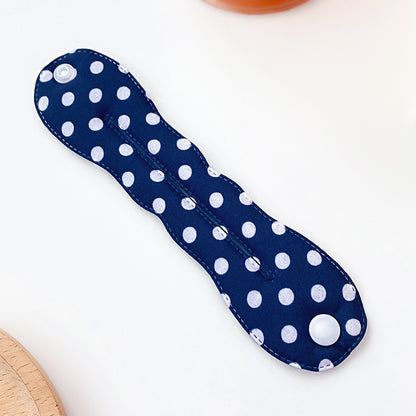 Navy blue cloth pad with white polka dots on a light background