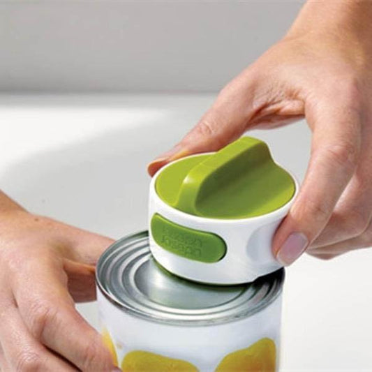Person using a green can opener on a can with a white background