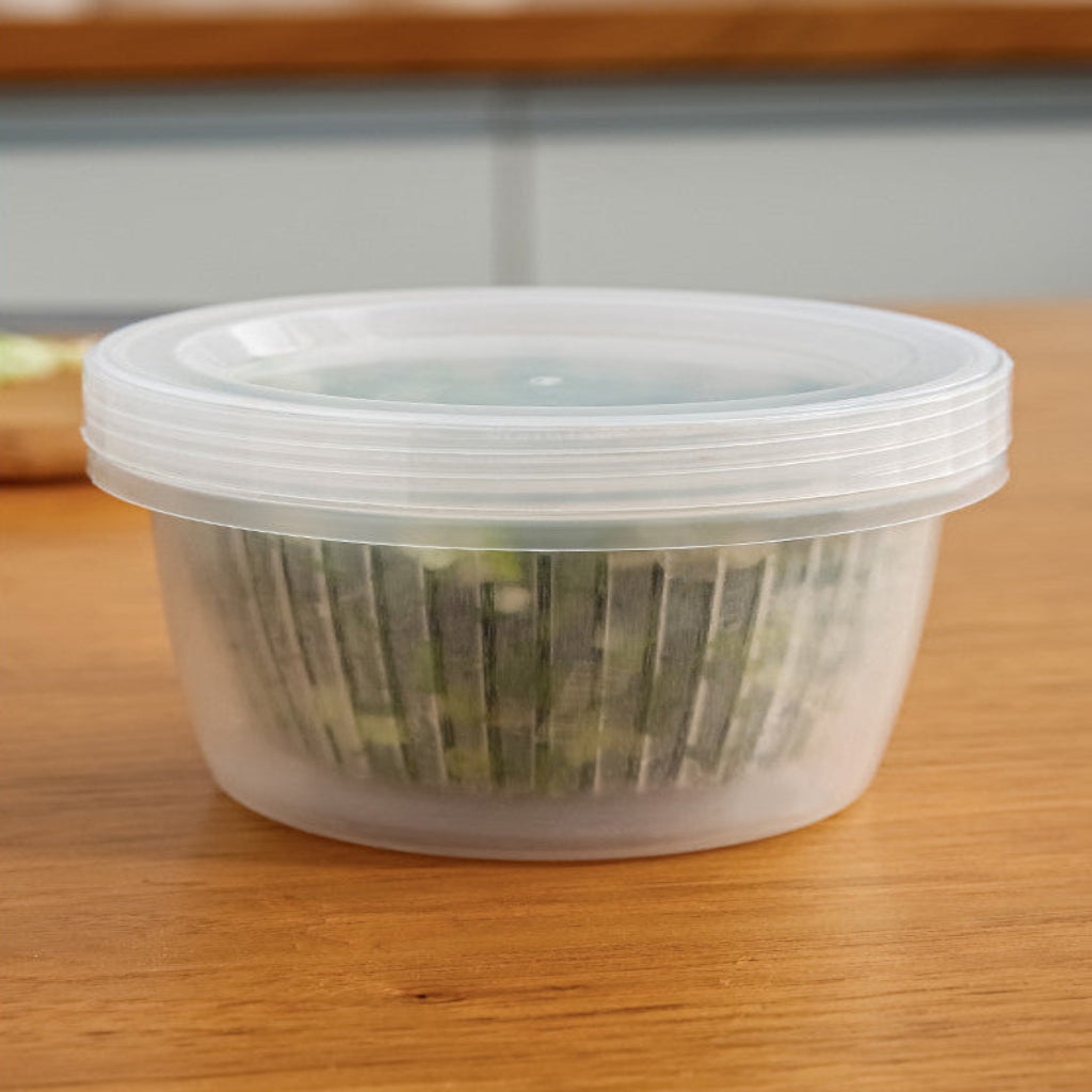 Clear container with green plants on a wooden surface