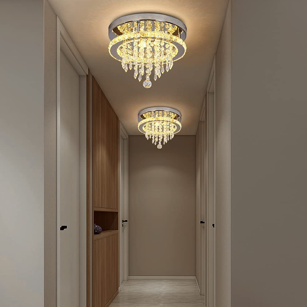 Chandelier in a hallway with neutral walls and wooden cabinet.
